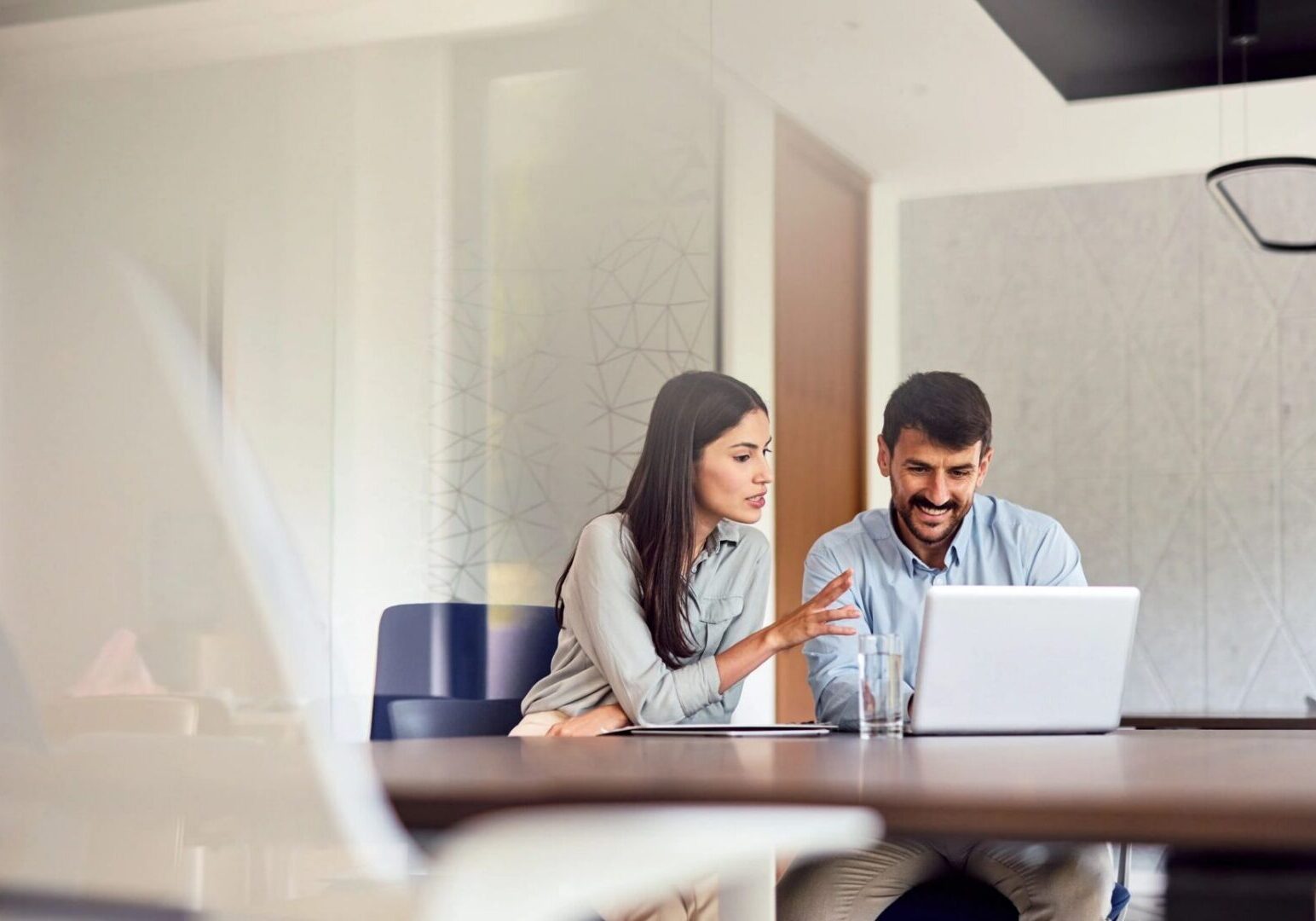 Colleagues discussing work at a laptop