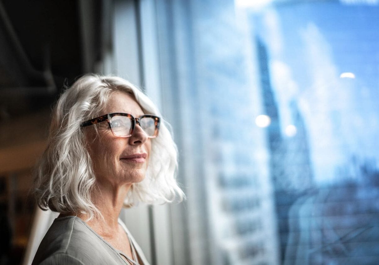 Woman with glasses looking out window