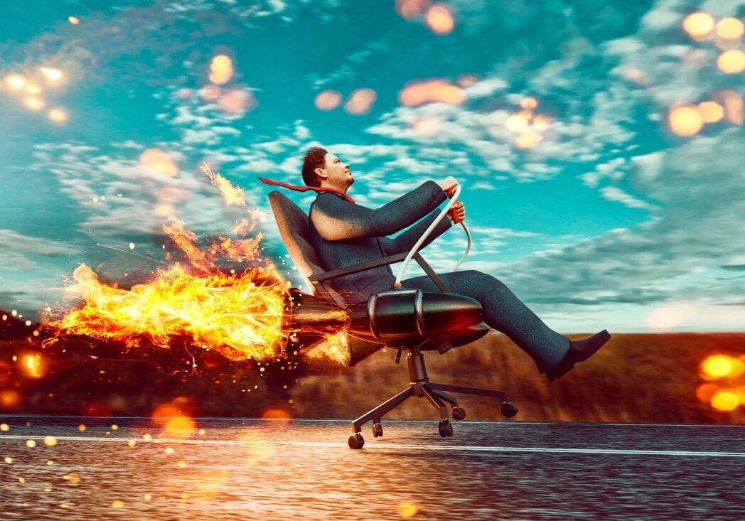 Man riding flaming office chair outdoors