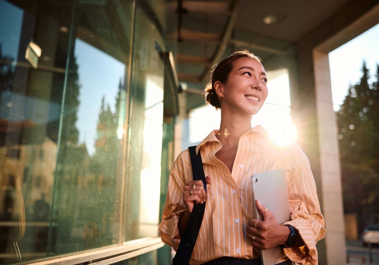 Happy woman carrying laptop in sunlight